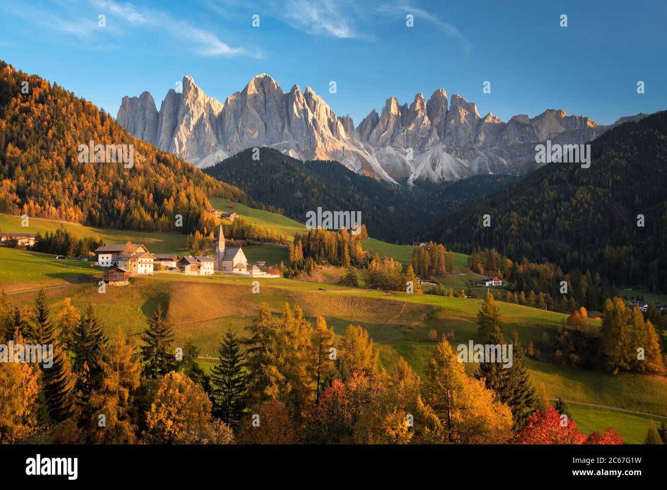 Kirche im Dorf Sankt Magdalena in Villnoess in einer Herbstlandschaft mit den Geisler Dolomiten Berggipfeln im Rücken in Südtirol, Italien. Stockfoto