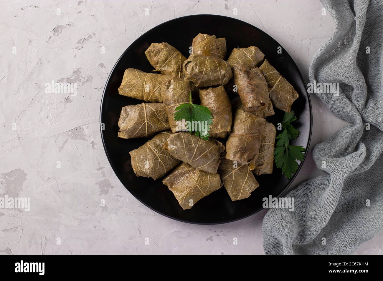 Dolma - gefüllte Traubenblätter mit Reis und Fleisch auf schwarzem Teller auf hellgrauem Hintergrund. Traditionelle kaukasische, griechische, osmanische und türkische Küche Stockfoto