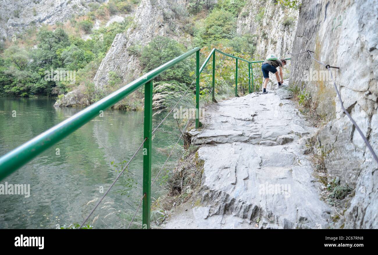 Am Matka Canyon, in der Nähe von Skopje, bindet ein Wanderer seine Schuhbahn.Besucher können den Weg neben dem Fluss Treska und dem ruhigen Wasser des Matka Sees laufen. Stockfoto