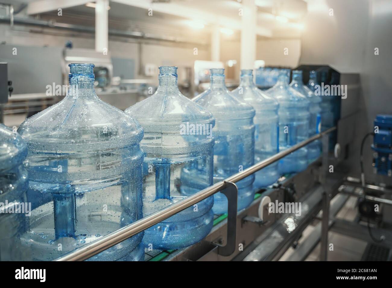 PET-Flaschen oder Gallonen aus Kunststoff auf Produktionslinie oder Förderband in der Wasserfabrik zum Abfüllen von reinem Trinkwasser. Stockfoto