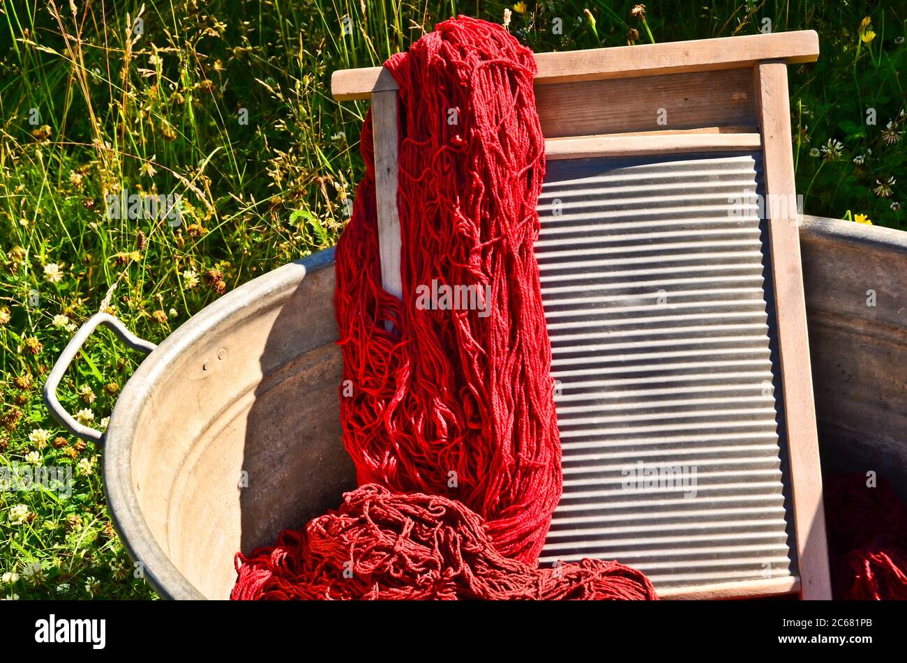 Ein altmodischer Waschtrougt gefüllt mit gefärbten und gewaschenen Schnüren und Seilen aus roter Wolle Stockfoto