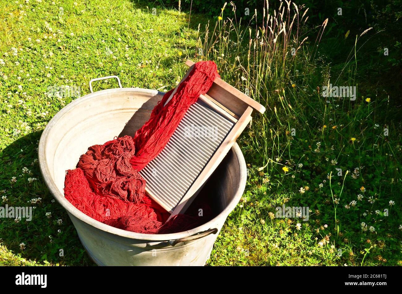 Ein altmodischer Waschtrougt gefüllt mit gefärbten und gewaschenen Schnüren und Seilen aus roter Wolle Stockfoto