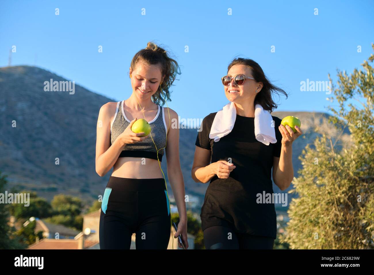 Sportlich gesunde Familienleben, glückliche Mutter und Tochter im Teenageralter essen Äpfel Stockfoto