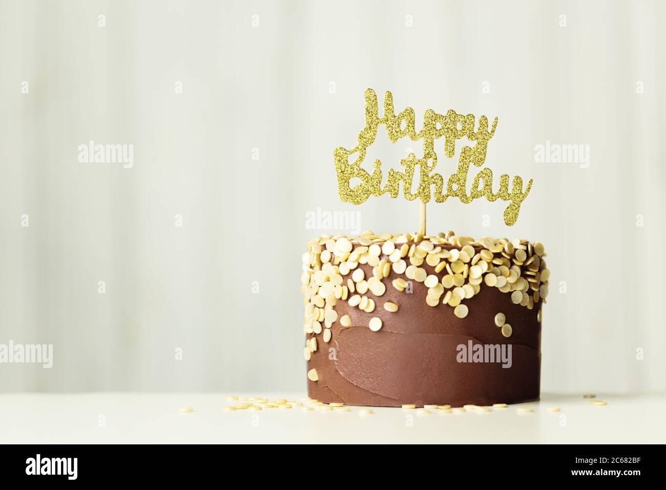 Schokoladen-Geburtstagskuchen mit goldenem 'Happy Birthday'-Schild Stockfoto