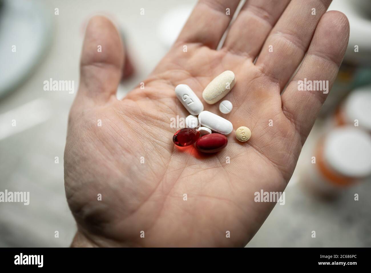 Männliche Hand hält eine Vielzahl von Vitaminen und verschreibungspflichtigen Pillen Stockfoto