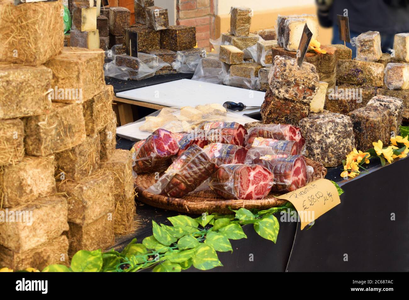 Verschiedene italienische Käsesorten und typische Salami zum Verkauf auf einem Straßenmarkt im mittelalterlichen Dorf Asciano in Siena, Toskana in Italien Stockfoto