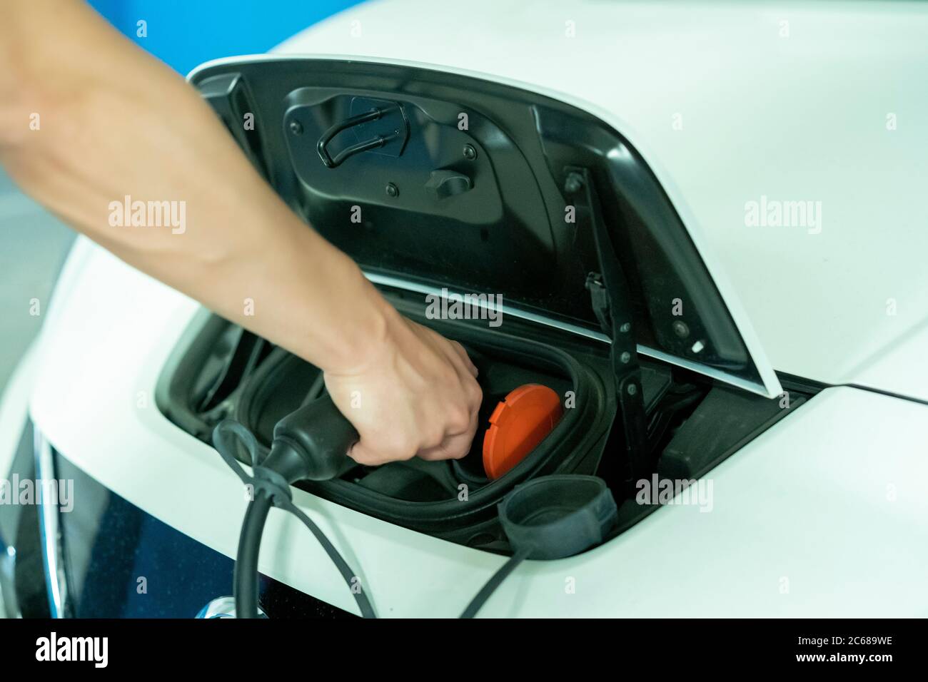 Junger Mann lädt sein umweltfreundliches Elektrofahrzeug Stockfoto