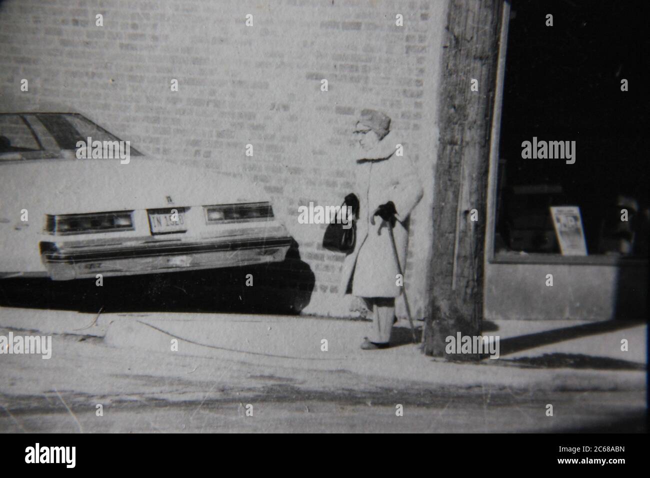 Feine 70er Jahre Vintage schwarz-weiß Lifestyle-Fotografie einer Dame, die die Straße überquert. Stockfoto
