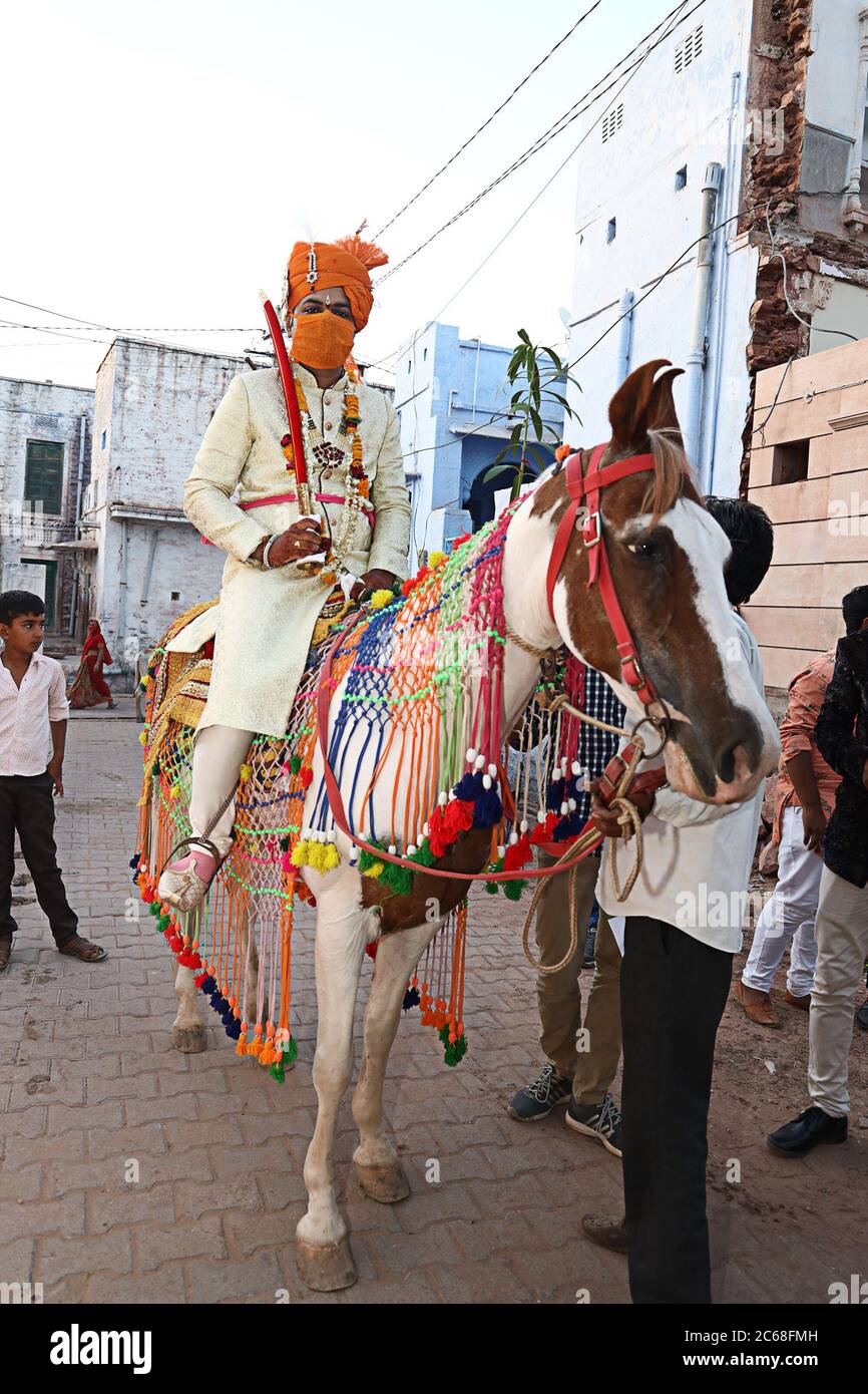 Jodhpur, Rajashtbn, Indien. 30. Juni 2020: Indische Bräutigam trägt Schutzmaske mit Schwert in der Hand auf Pferd sitzend, Baarat Lock down endet mit Sicherheit m Stockfoto