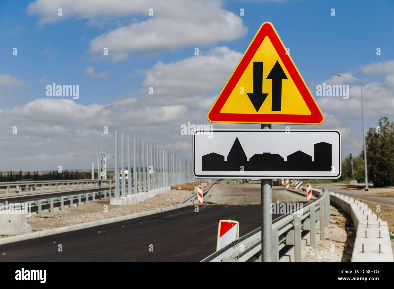 Temporäre Verkehrszeichen zwei-Wege-Verkehr und Verkehrszeichen den Anfang des Dorfes gegen den Himmel und die Straße im Bau. Stockfoto