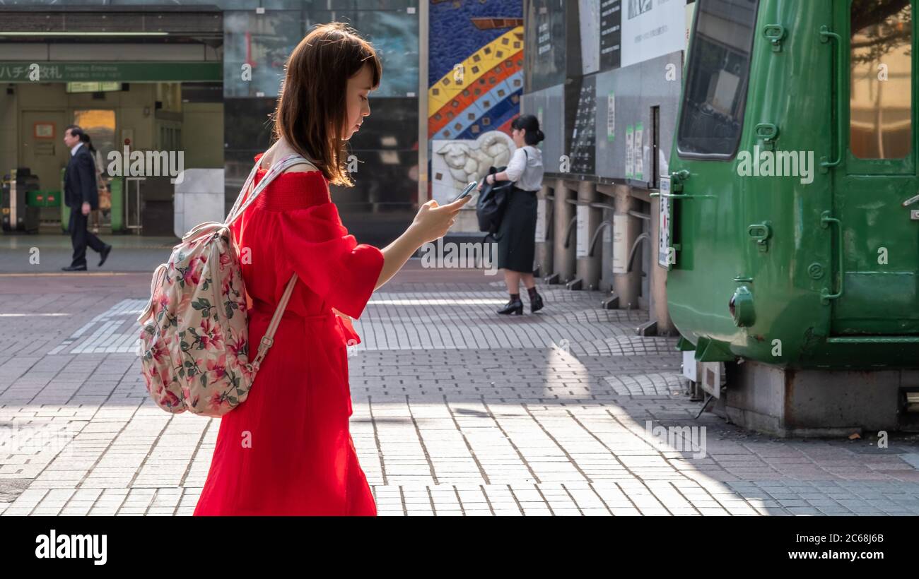 Mädchen mit Smartphone zu Fuß auf Shibuya Hachiko Square Tokyo, Japan Stockfoto