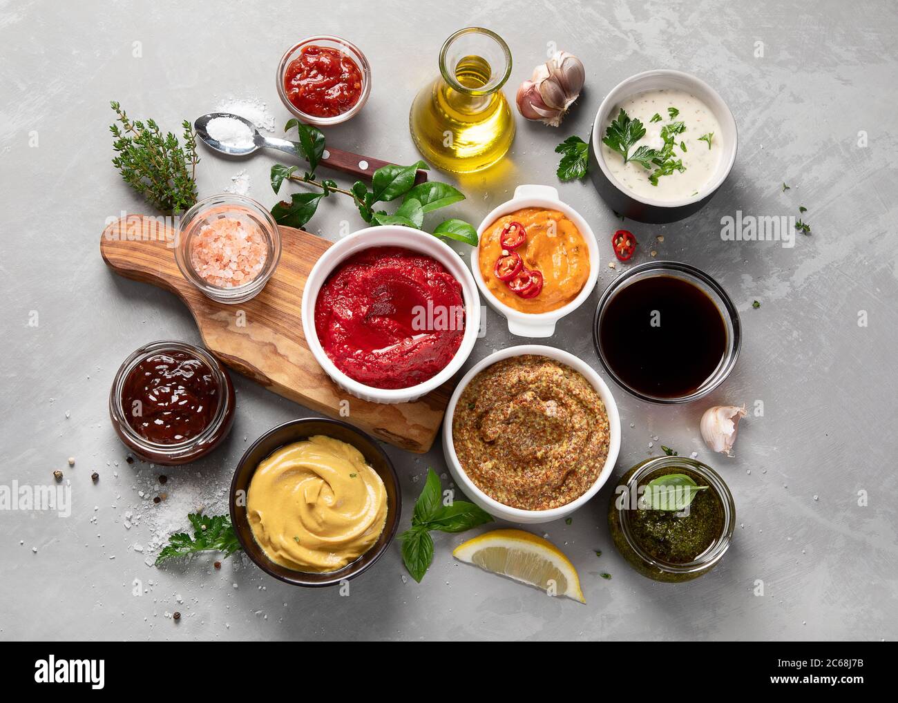 Set aus verschiedenen Saucen in Schalen auf grauem Hintergrund. Draufsicht mit Kopierbereich Stockfoto