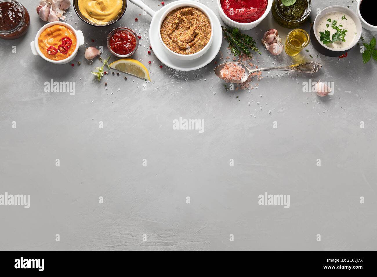 Set aus verschiedenen Saucen in Schalen auf grauem Hintergrund. Draufsicht mit Kopierbereich Stockfoto