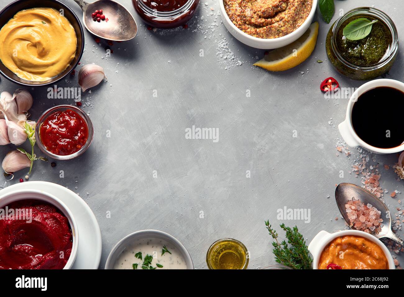 Set aus verschiedenen Saucen in Schalen auf grauem Hintergrund. Draufsicht mit Kopierbereich Stockfoto