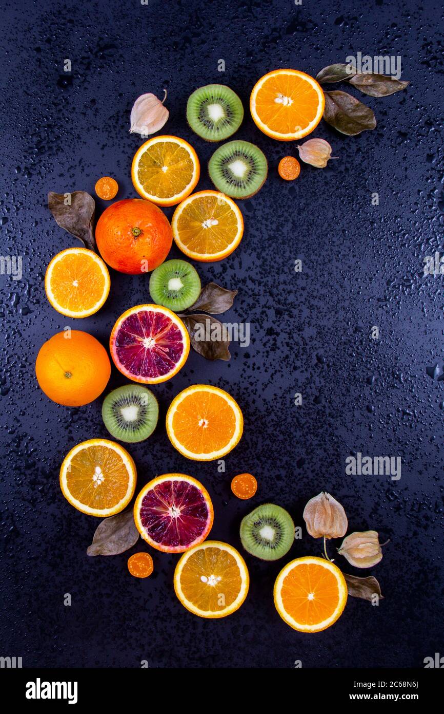 Eine Kombination aus Kapgoosebeery und ganzen Orangen und geschnittenen Orangen und Kiwis mit schwarzem Hintergrund. Stockfoto