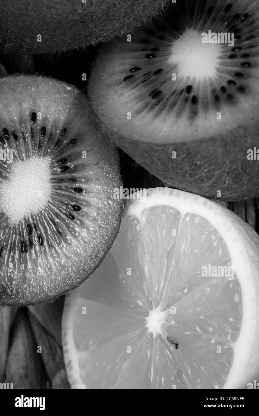 Schwarz-weiße Obstfotografie von einigen gehackten Zitronen und Kiwis. Stockfoto