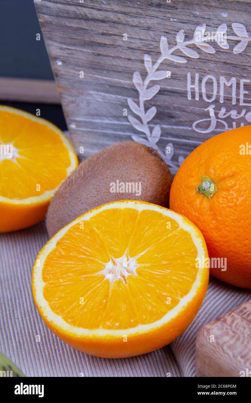 Eine gestaltete Fotografie von einer halbierten Orange und Kiwis im Hintergrund. Stockfoto