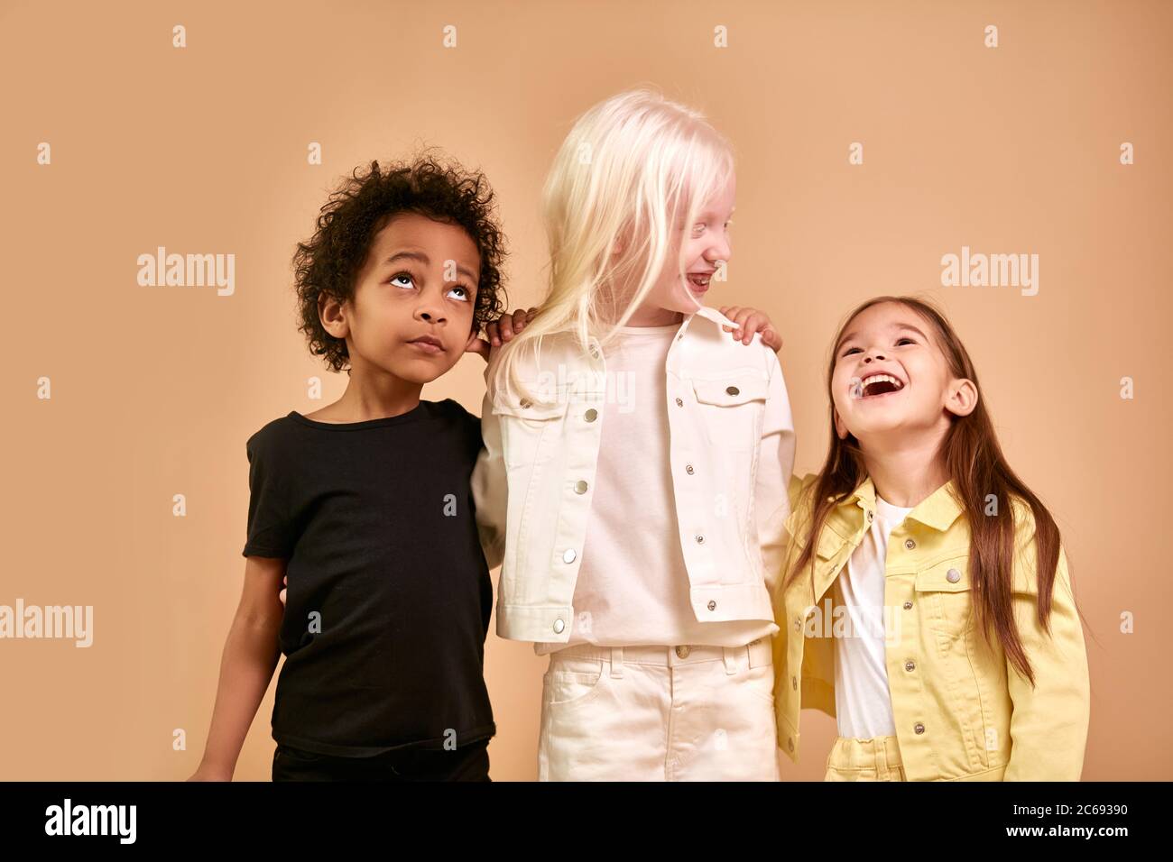 Portrait von fröhlichen positiven Kinder, multiethnische Kinder isoliert im Studio. Liebenswert afro junge und Albino, kaukasischen Mädchen stehen zusammen, posiert. Int Stockfoto