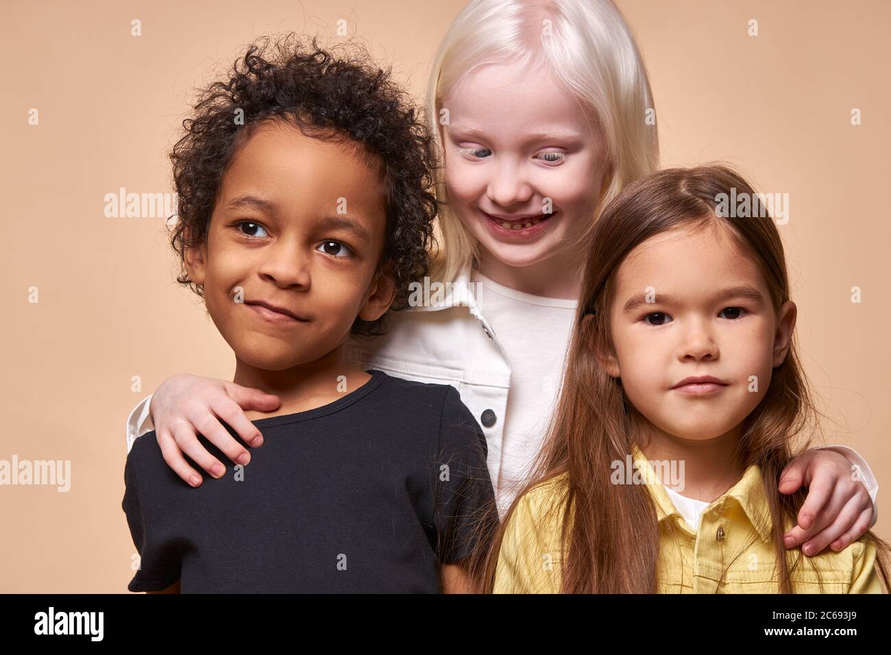 Portrait von fröhlichen positiven Kinder, multiethnische Kinder isoliert im Studio. Liebenswert afrikanamerikanischen schwarzen Jungen und Albino, kaukasischen Mädchen stehen toge Stockfoto