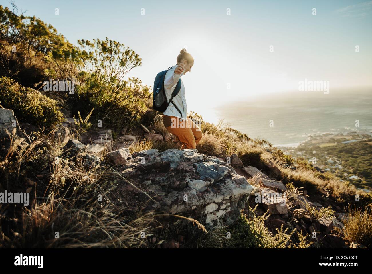 Frau mit Rucksack, die den Berg hinunter bewegt. Weibliche Bergsteigerin, die die Klippe hinuntergeht. Stockfoto