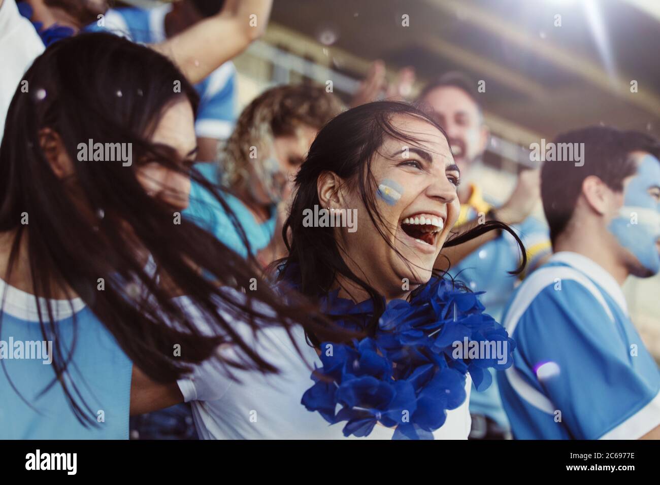 Menge von Sportfans aus Argentinien jubeln während eines Spiels im Stadion. Gruppe von Freunden beobachten Sportspiel feiern, wenn ihr Team erzielte ein Tor Stockfoto