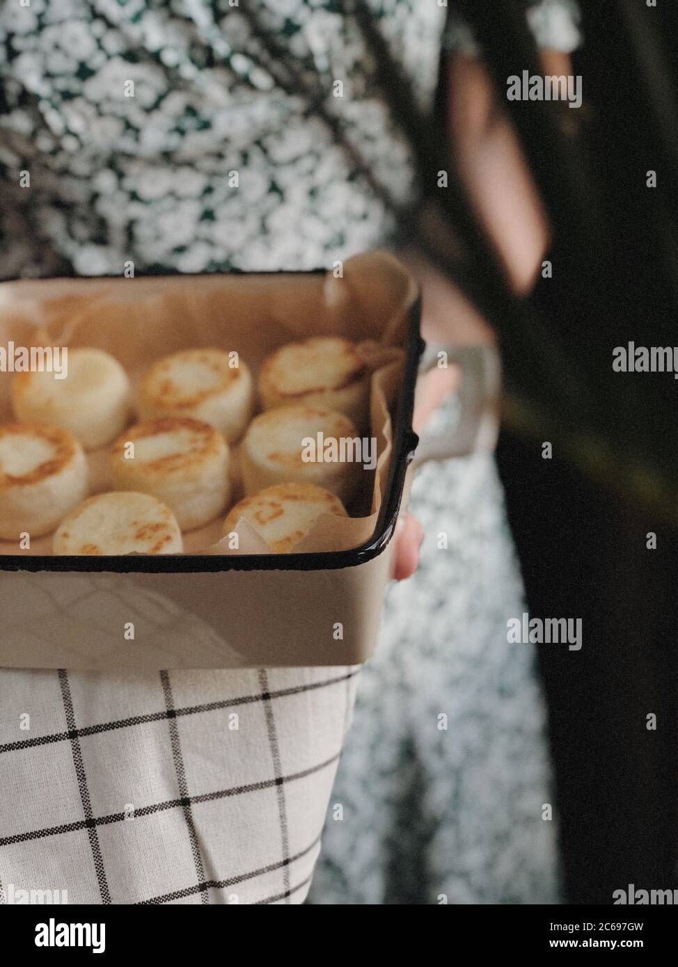 Frau hält ein Gericht mit Käsekuchen Stockfoto