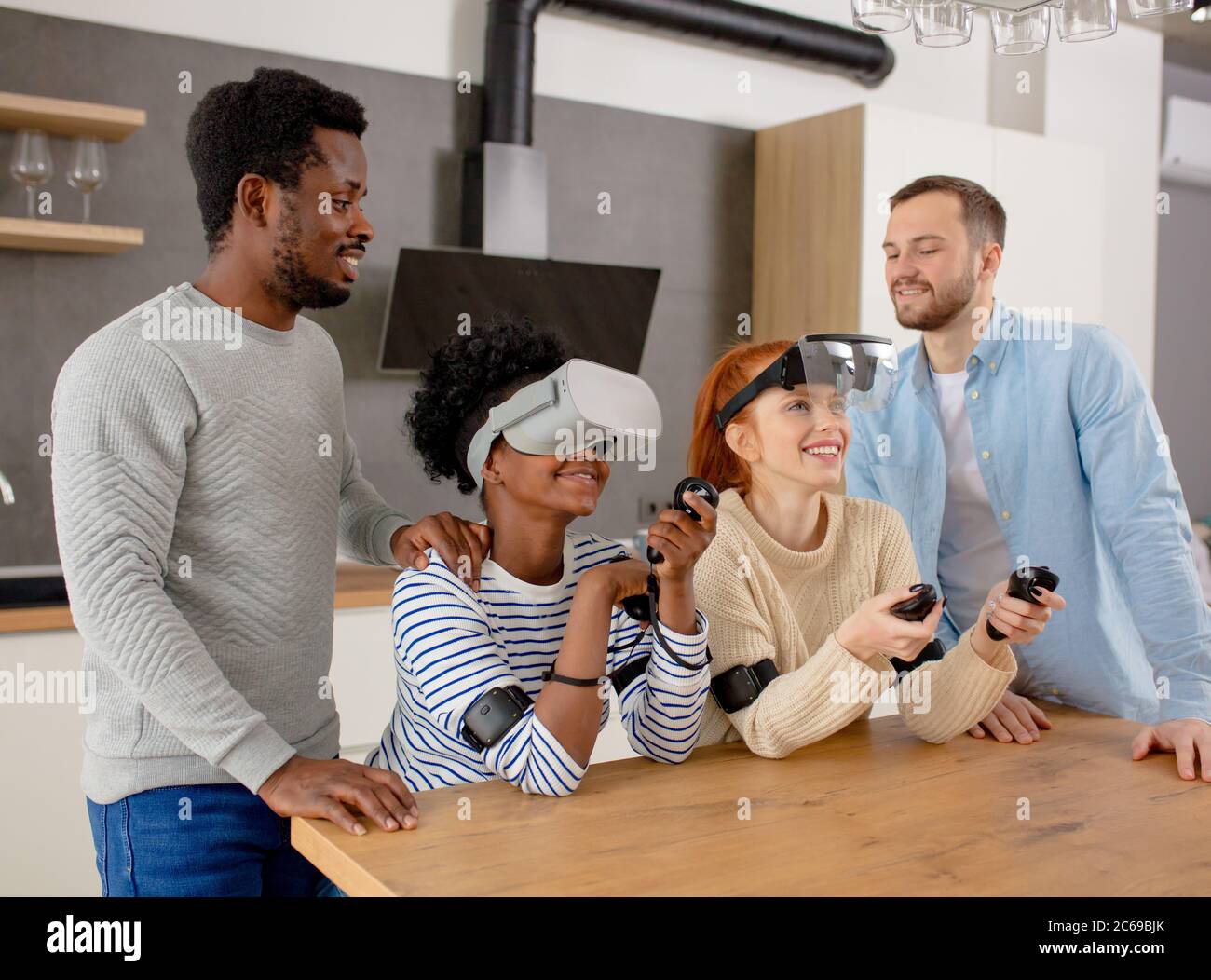 Virtuelle Schlacht von zwei Multirassischen Teams, bestehend aus liebevolle afrikanische und kaukasische Paare spielen in virtuellen Spielen Jungs unterstützen und unterrichten die Stockfoto