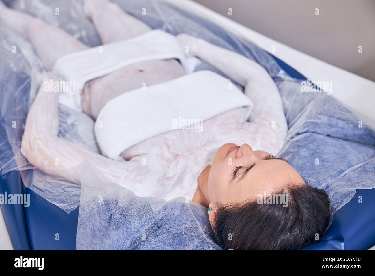 Junge Dame liegt mit Handtüchern auf ihrem Körper im Spa-Salon Stockfoto