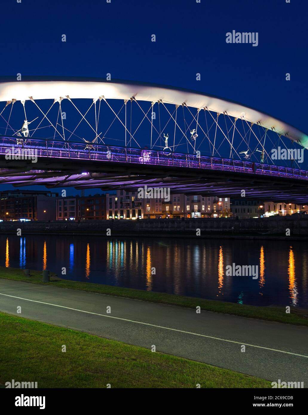 Pater Bernatek Fußgängerbrücke beleuchtet in der Nacht mit Reflexionen im Fluss - Krakau, Polen Stockfoto