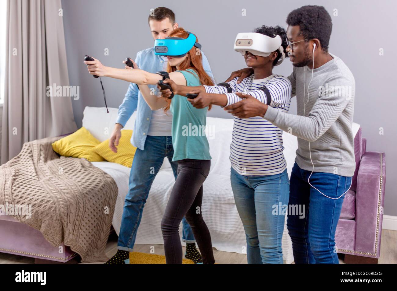 Virtuelle Schlacht von zwei Multirassischen Teams, bestehend aus liebevolle afrikanische und kaukasische Paare spielen in virtuellen Spielen Jungs unterstützen und unterrichten die Stockfoto