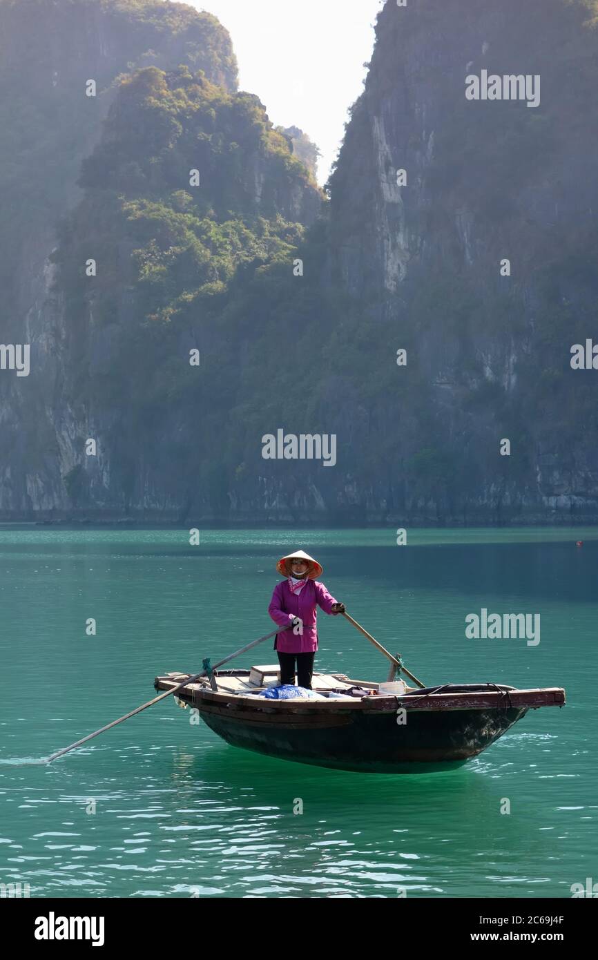 Eine Vietnamesin mit Reismütze rudert ein Bambusboot im Fischerdorf Vung Vieng in der Ha Long Bay, Vietnam Stockfoto