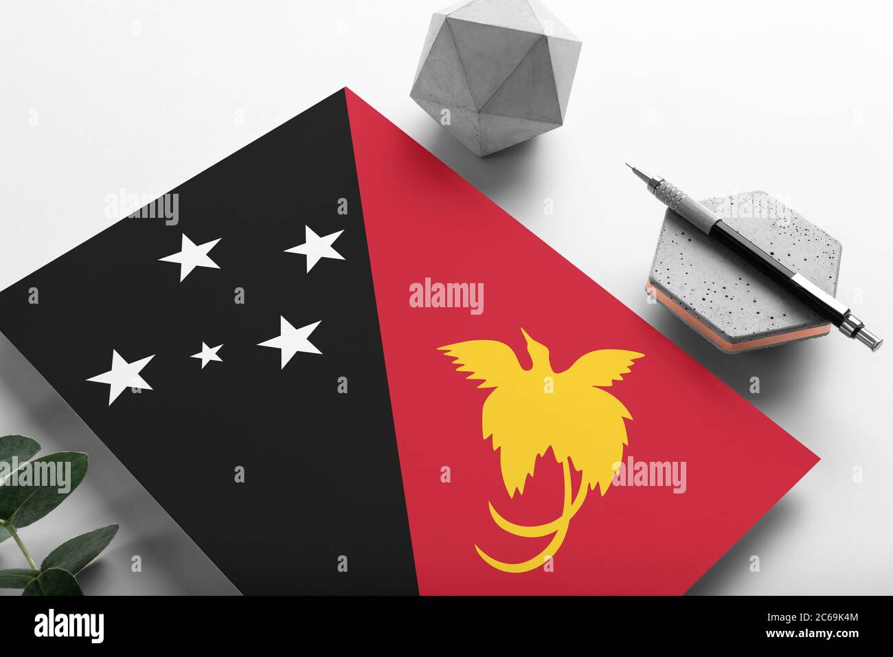 Papua-Neuguinea-Flagge auf minimalistischem Papierhintergrund. Nationale Einladung Brief mit stilvollen Stift auf Stein. Kommunikationskonzept. Stockfoto