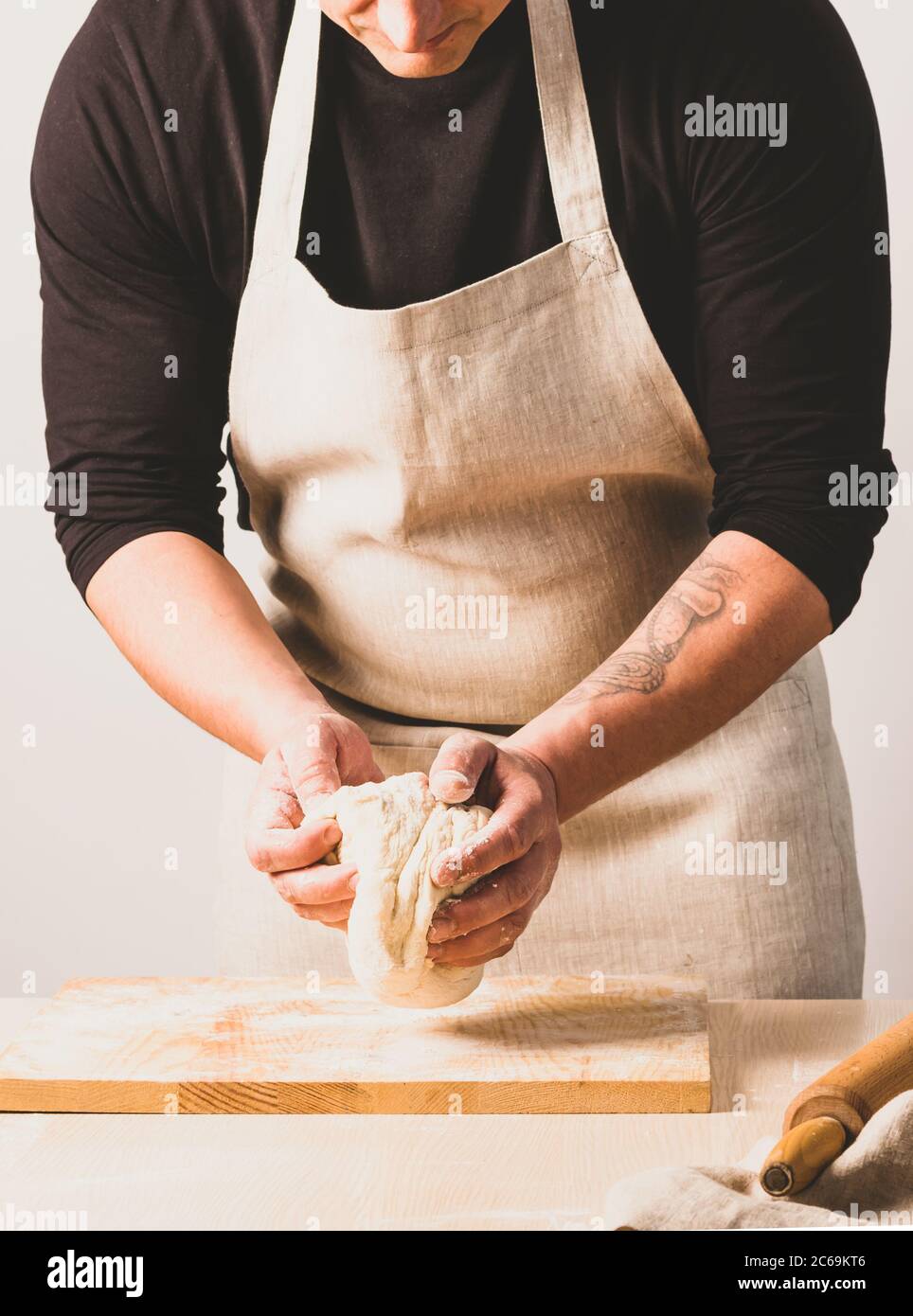 Konzept Prozess der Herstellung von alternativen Hefe-frei hausgemachtes Brot. Ein Mann knetet einen Knettopf mit Teig auf dem Tisch. Stockfoto