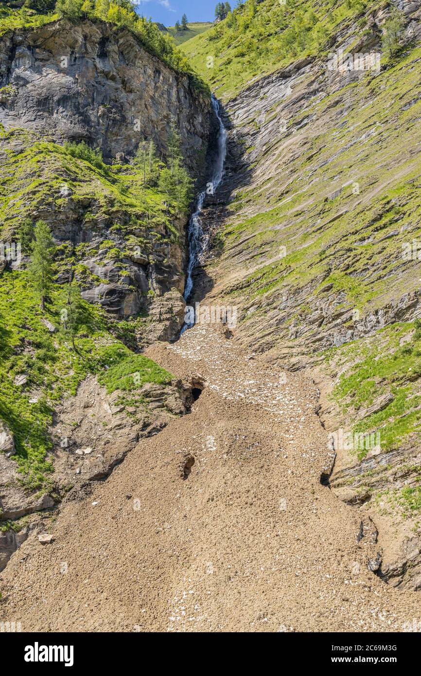 Schmelzwasser fließt ab und fällt die Klippe hinunter auf einen Lawinenabbruchkegel, Österreich, Kärnten, Nationalpark hohe Tauern Stockfoto