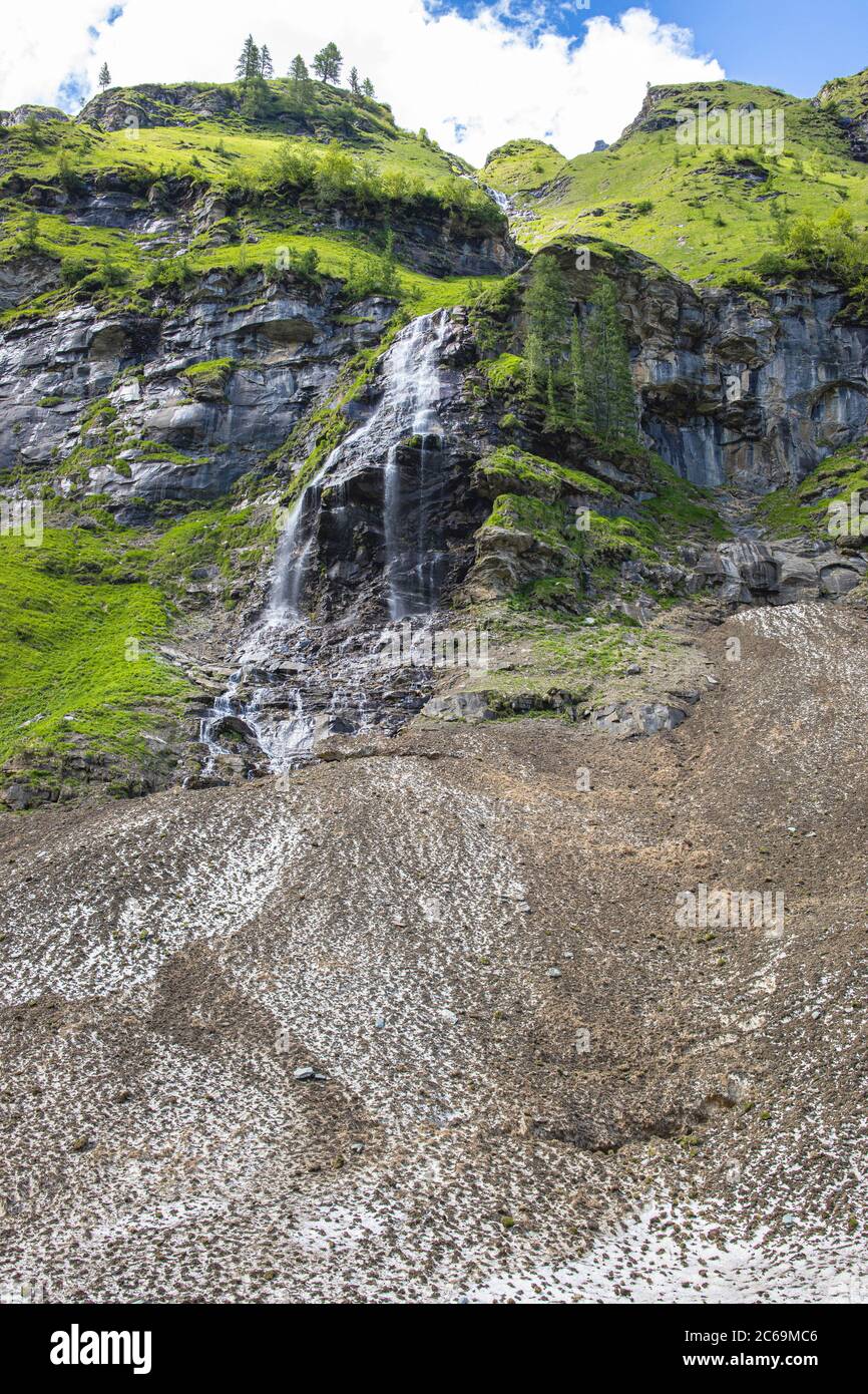 Schmelzwasser fließt ab und fällt die Klippe hinunter auf einen Lawinenabbruchkegel, Österreich, Kärnten, Nationalpark hohe Tauern Stockfoto