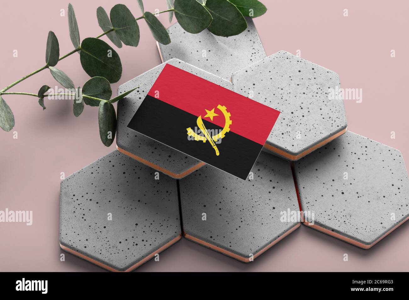 Angola Flagge auf Sechseck stilvolle Steine. Rosa Hintergrund für Kopierbereich. Flach liegend, Draufsicht minimales nationales Konzept. Stockfoto