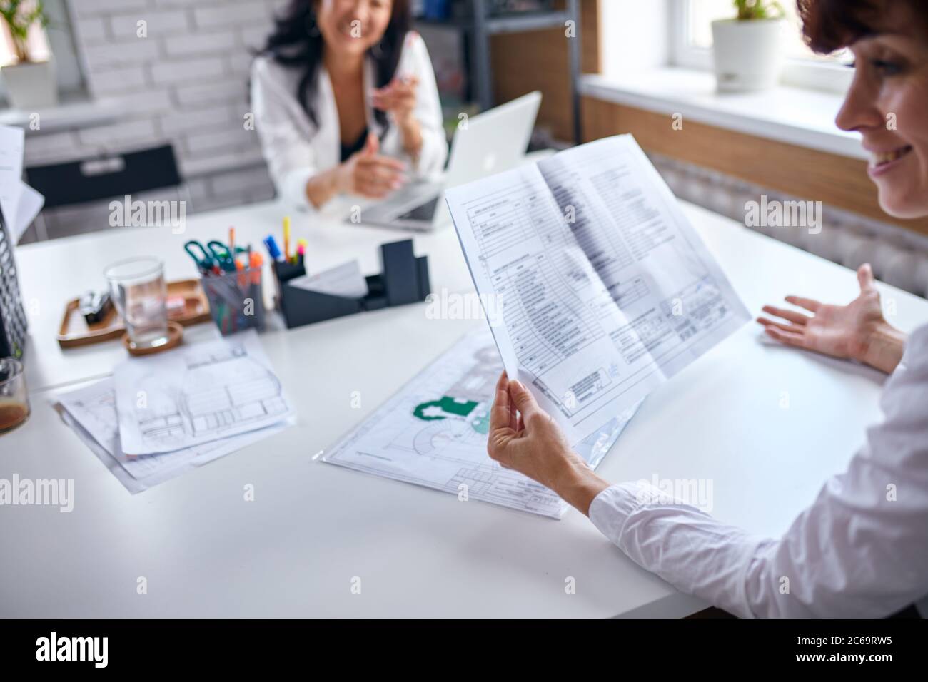 Schöne asiatische Direktor der Firma hören kaukasischen Vertreter hält Papiere Stockfoto