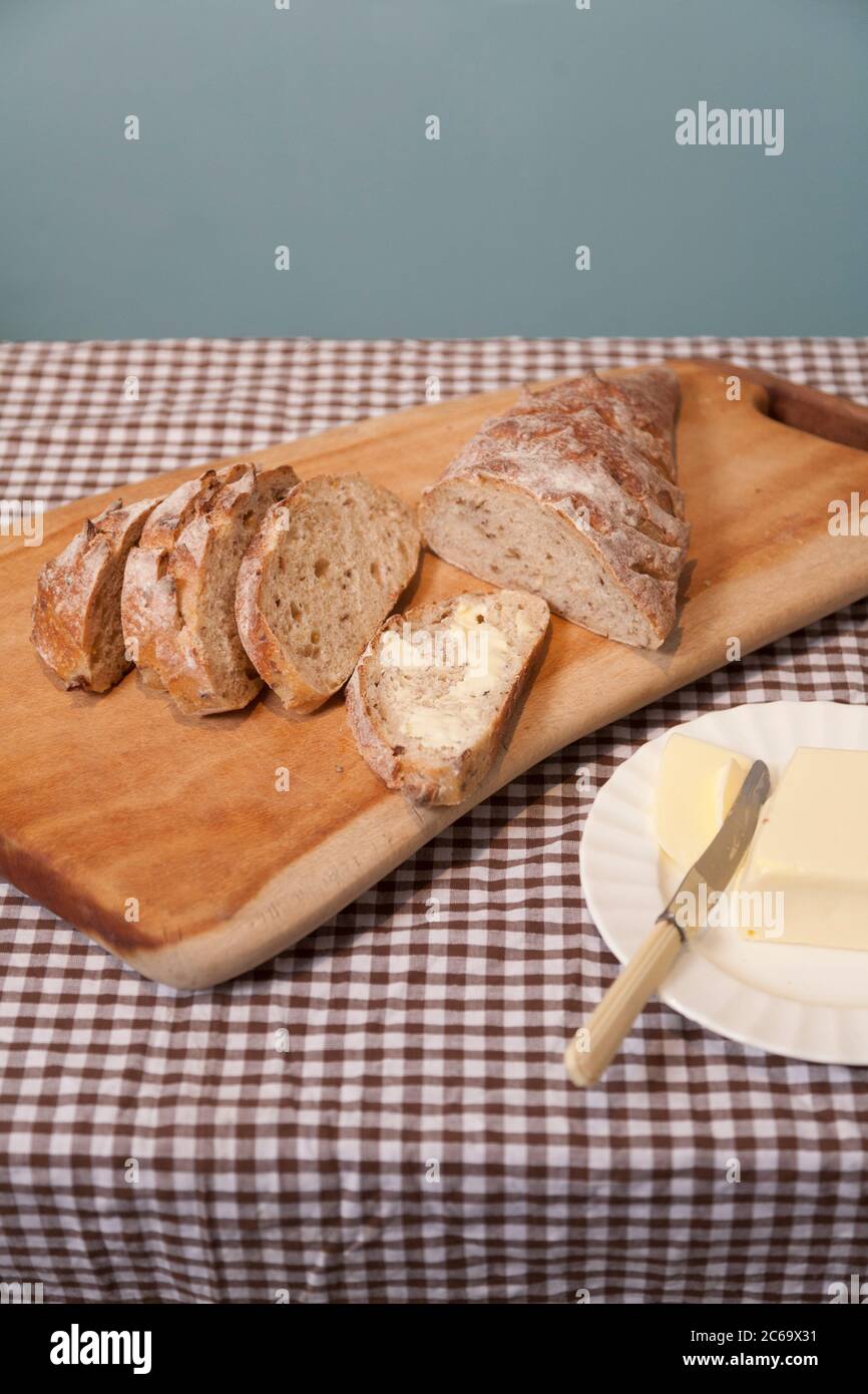 Sauerteig Brot mit Rosinen und gemischte Schale vom Bauernmarkt in Stroud auf einem handgemachten Brottafel geschnitten und mit Butter serviert. Stockfoto