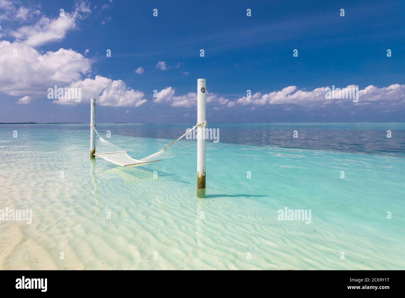 Tropisches Chill-Out, luxuriöser Strand mit Hängematte über dem Wasser, endloser Meerblick, exotische Meereslandschaft. Sommerurlaub, Urlaubsziel, entspannen und friedlich Stockfoto