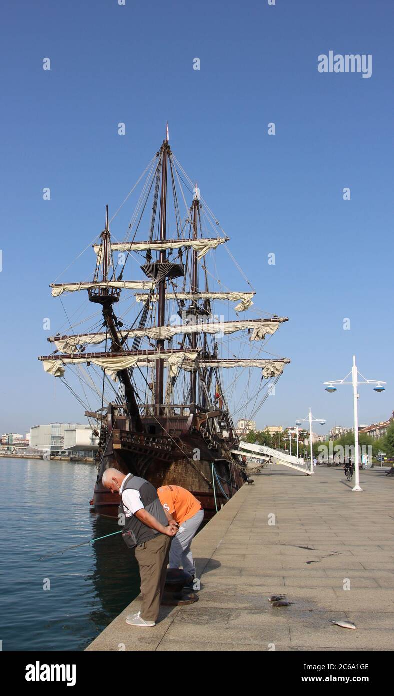 Angeln vor der Nachbildung des Victoria-Schiffes eine Karacke und das erste Schiff, das den Globus umrundet, vor Anker in Santander mit starkem Sonnenlicht Stockfoto
