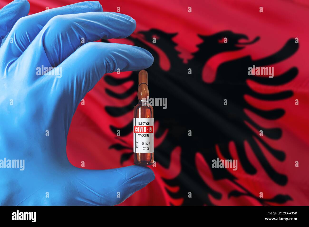 Albanien Flagge mit Coronavirus Covid-19 Konzept. Arzt mit blauen Schutzhandschuhen mit einer Impfstoffflasche. Epidemic Virus, Cov-19, Corona vi Stockfoto
