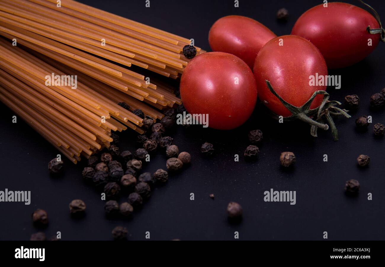 Pasta in Form und Pasta in Form. Pasta in verschiedenen Formen und Farben mit Tomaten und Pfefferkörnern. Stockfoto