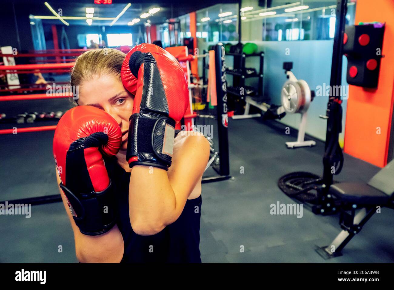 Junge Frau trainiert Kickboxen in einem Studio für gesundes Leben und Selbstverteidigung. Sie trägt schwarze und rote Boxhandschuhe Stockfoto
