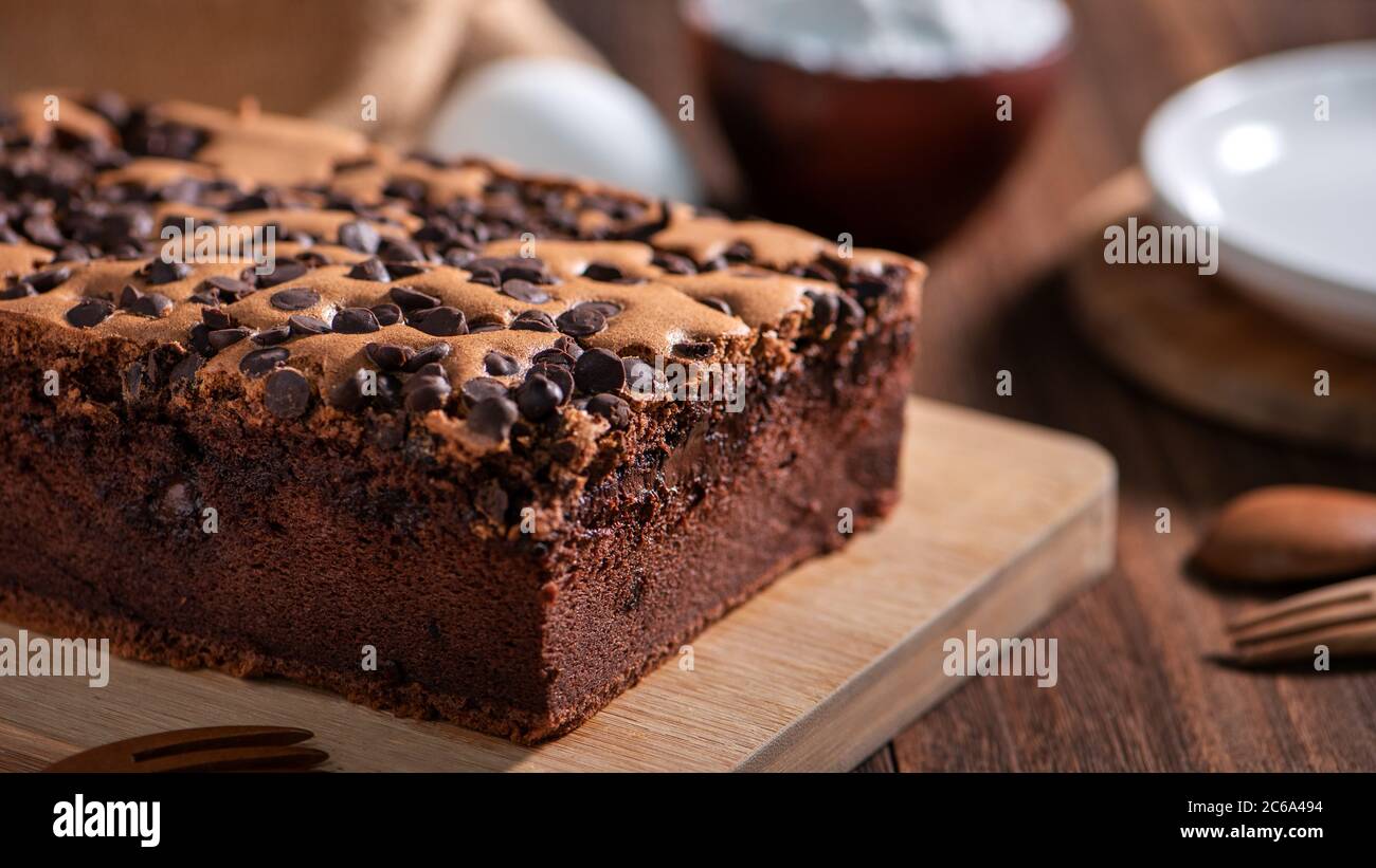 Schokoladengeschmack taiwanesische traditionelle Biskuitkuchen (taiwanesische castella kasutera) auf einem Holztablett Hintergrund Tisch mit Zutaten, close up. Stockfoto