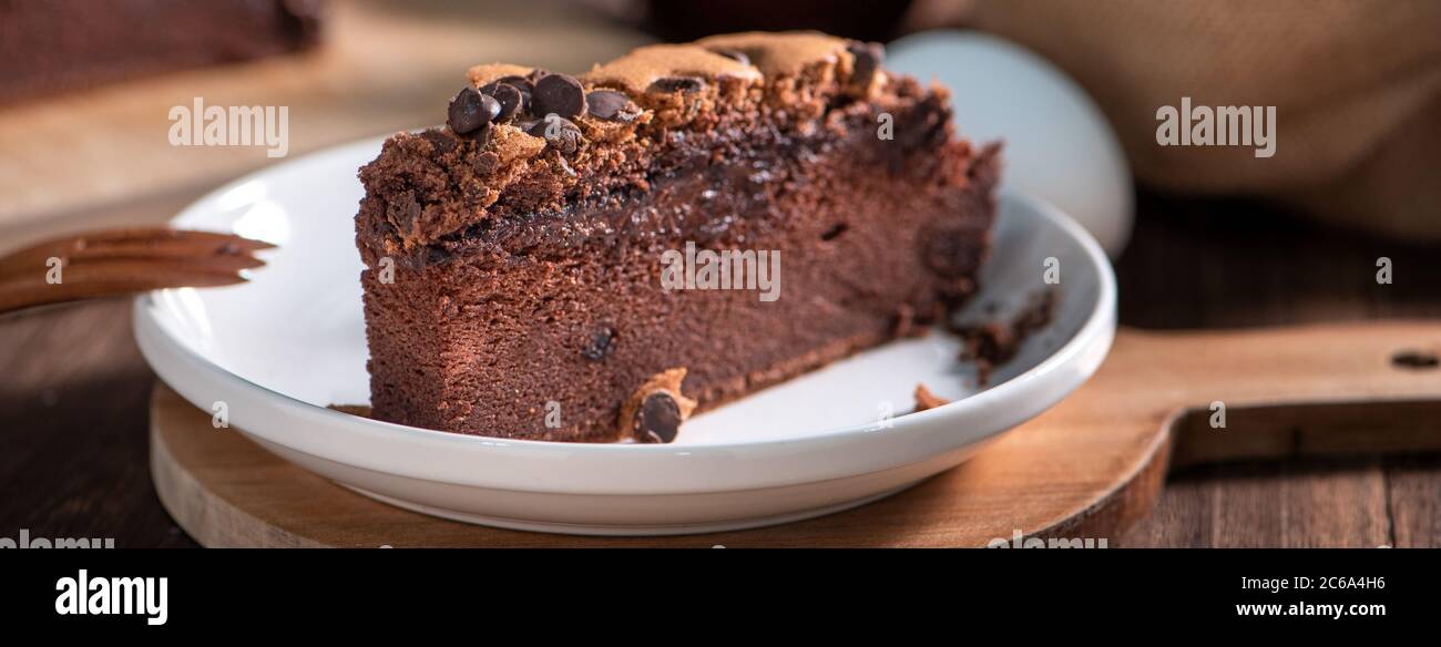 Schokoladengeschmack taiwanesische traditionelle Biskuitkuchen (taiwanesische castella kasutera) auf einem Holztablett Hintergrund Tisch mit Zutaten, close up. Stockfoto