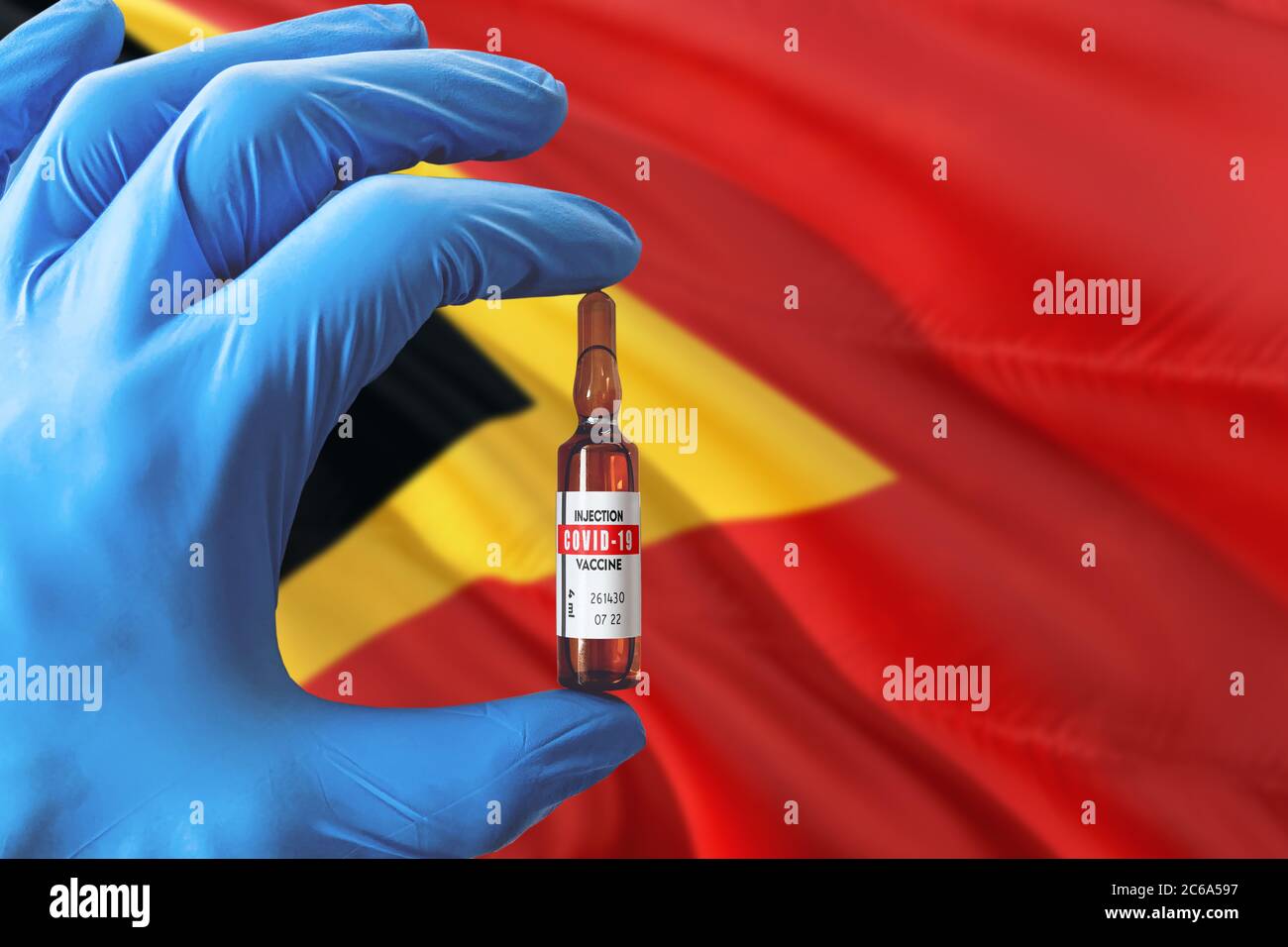 Osttimor Flagge mit Coronavirus Covid-19 Konzept. Arzt mit blauen Schutzhandschuhen mit einer Impfstoffflasche. Epidemic Virus, Cov-19, Corona Stockfoto