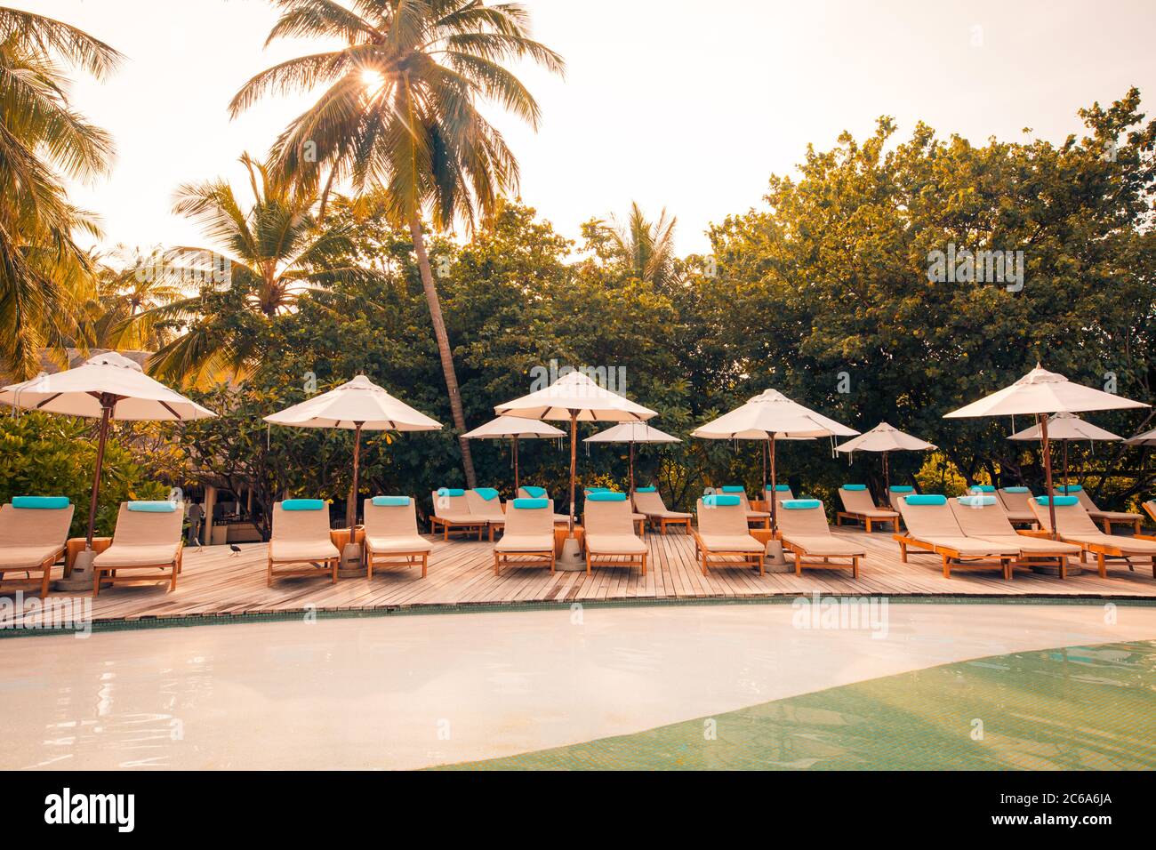 Wunderschöner tropischer Strand im Resort Hotel Island. Pool mit Stühlen, Liegestuhl unter Sonnenschirm und Palmen. Sommerurlaub, Urlaubsreisekonzept Stockfoto