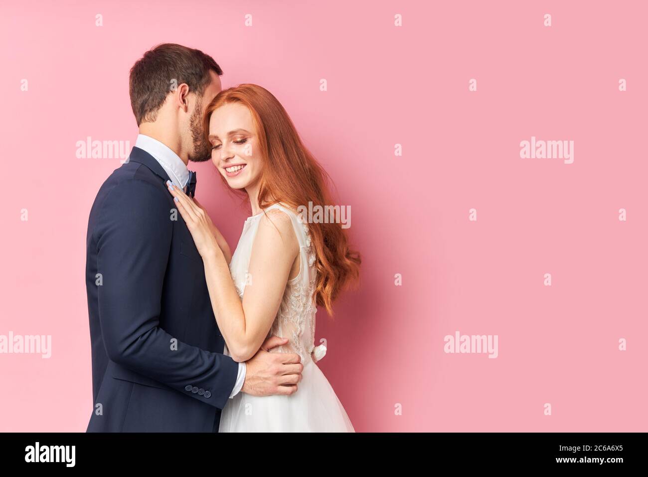 Schöne Frau mit roten Haaren umarmt ihren Verlobten in eleganten Anzug küssen sie. Glückliche junge Familie, Liebeskonzept Stockfoto