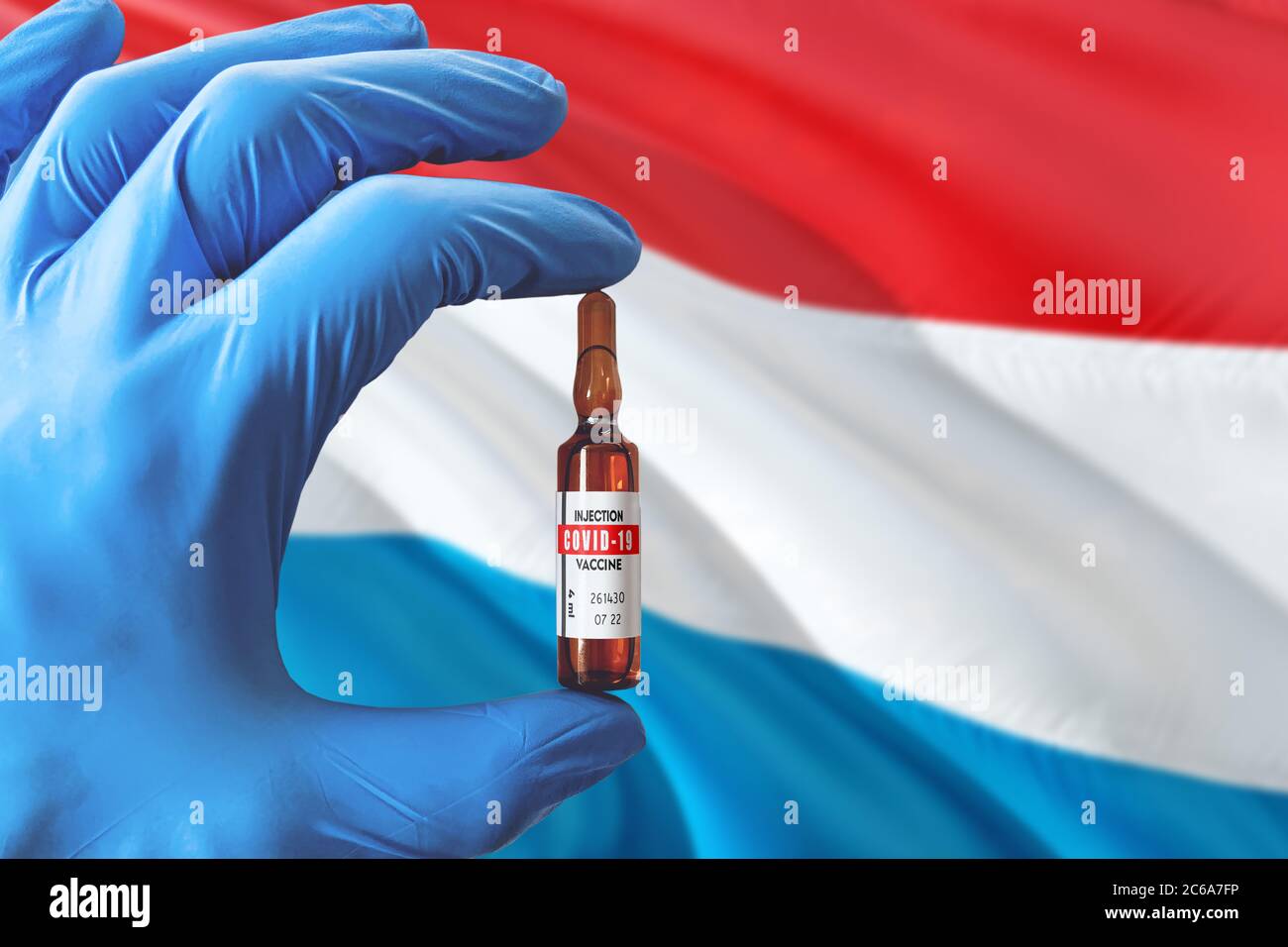 Luxemburg Flagge mit Coronavirus Covid-19 Konzept. Arzt mit blauen Schutzhandschuhen mit einer Impfstoffflasche. Epidemic Virus, Cov-19, Corona Stockfoto