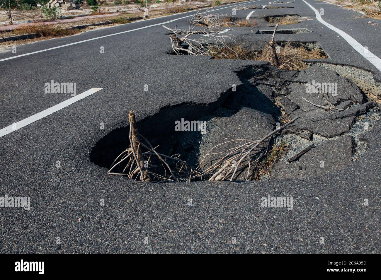 Die katastrophale Zerstörung der Asphaltstraße. Tiefe Löcher in der Leinwand. Schlechte Konstruktion der Autobahn-Bautechnik. Zerstörte Straße. Spule Stockfoto